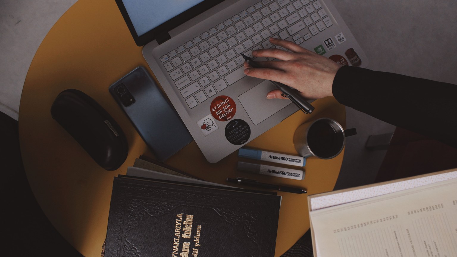 Overhead shot of a workspace in Turkey with a laptop, notebook, and coffee.